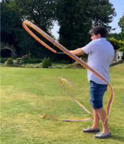 Click to enlarge Person frolicking with a ribbon on the grass outside the Autscape venue.